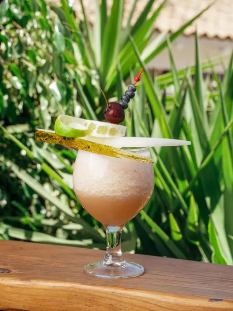 A frozen cocktail with a matcha-dusted pear slab and a cherry skewer.