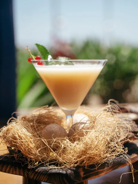 El Nido cocktail served in a straw nest with two chocolate eggs.